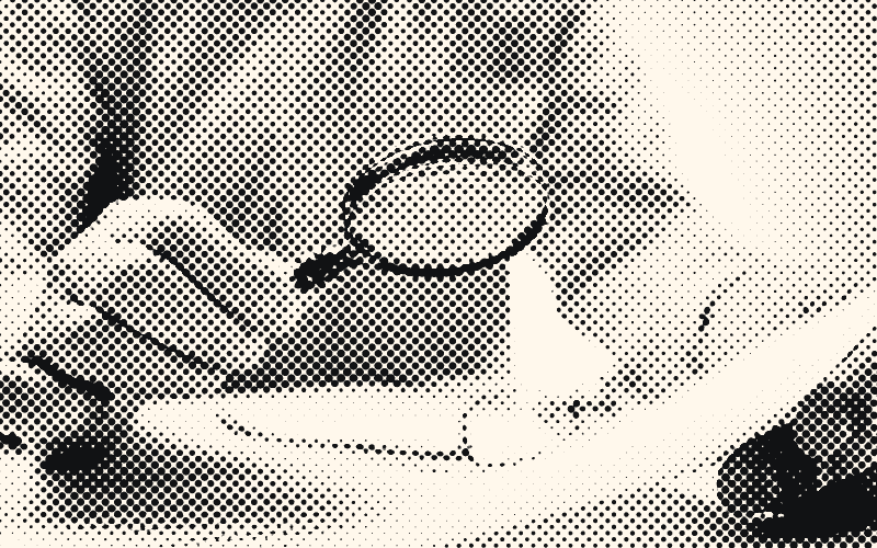 A person examines a document through a magnifying glass