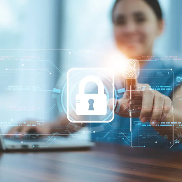 A woman sitting at a desk using a laptop with a padlock icon displayed on the screen.