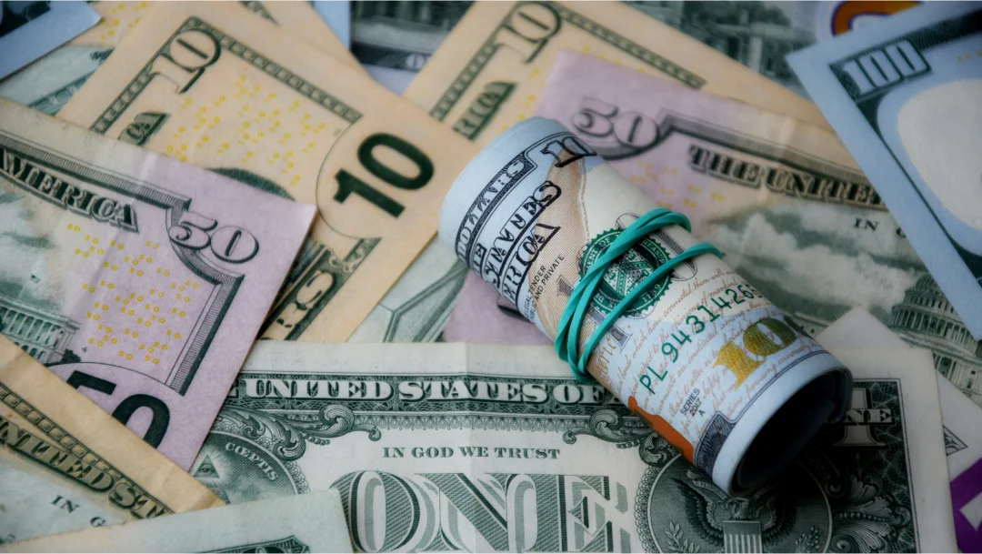 Un rouleau de billets repose sur une pile de dollars américains, symbolisant un prêt d'argent rapide.